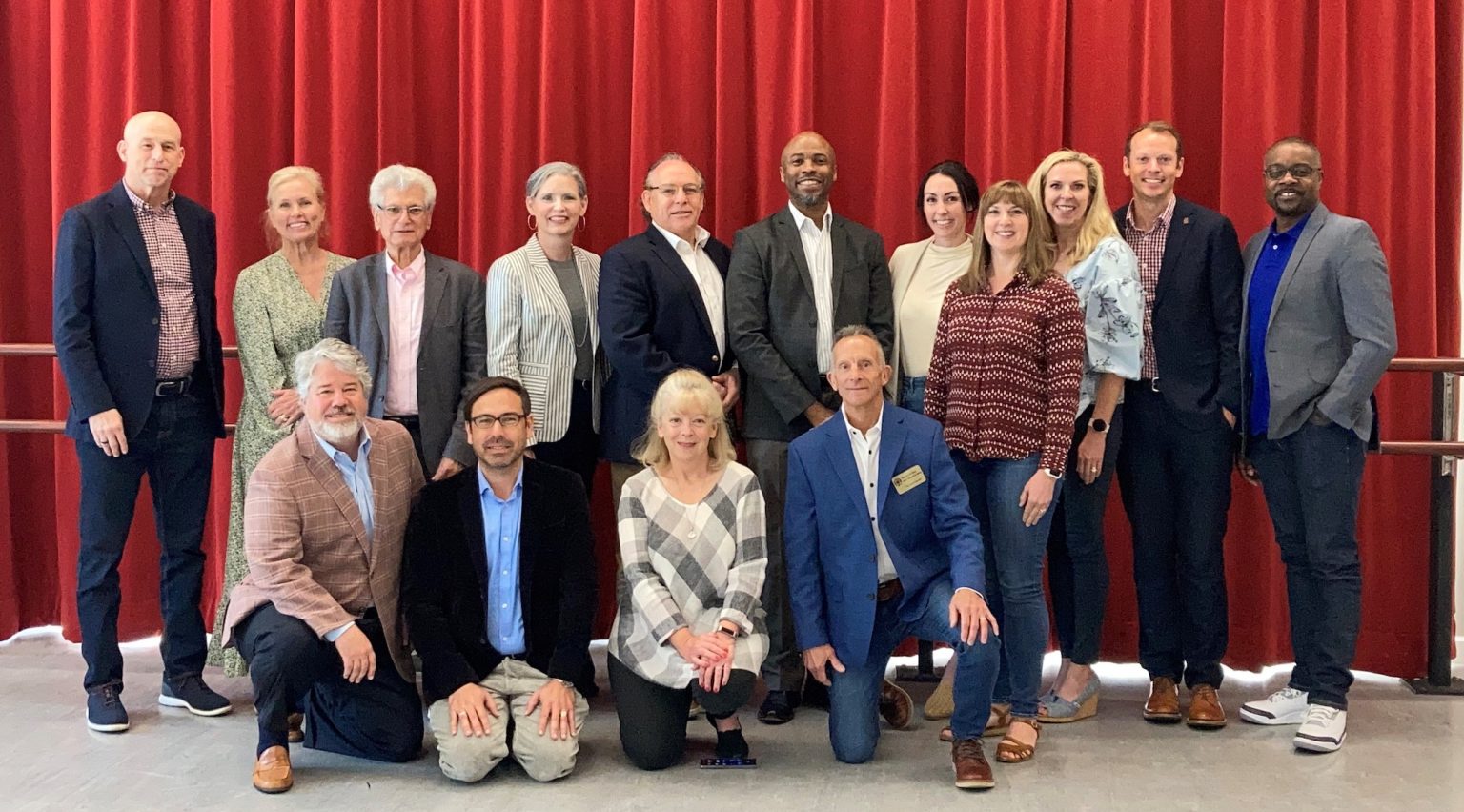 Council members in front of a red curtain.